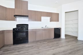 an empty kitchen with wooden cabinets and a black dishwasher