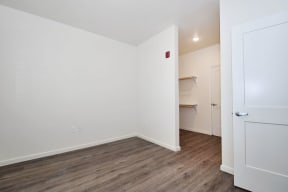 a bedroom with white walls and hardwood floors