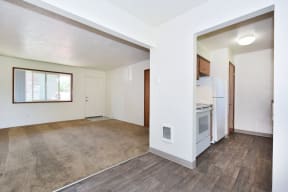an empty living room with a kitchen in the background