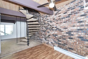 an exposed brick wall in a living room with a spiral staircase