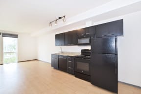 a kitchen with black cabinets and a wooden floor