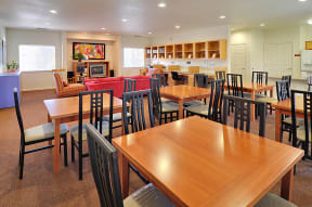 a dining area with tables and chairs and a kitchen in the background