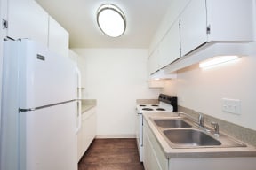 a small kitchen with white cabinets and a stainless steel sink