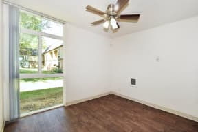 a bedroom with a large window and a ceiling fan