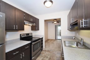 a kitchen with dark cabinets and a stainless steel sink