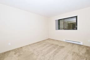 a bedroom with a large window and beige carpet
