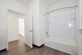 a white bathroom with a shower and a tub in a room with wood floors
