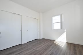 a bedroom with white walls and hardwood floors
