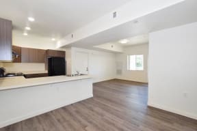 a kitchen and living room with white walls and wood floors