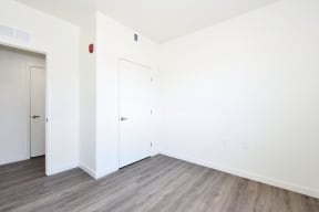 a bedroom with hardwood floors and white walls