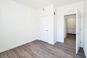 a bedroom with hardwood floors and white walls