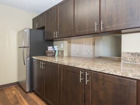 a kitchen with wooden cabinets and a granite counter top and a refrigerator