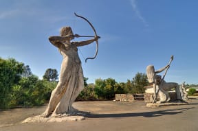 a statue of a woman shooting a bow and arrow next to a man with a