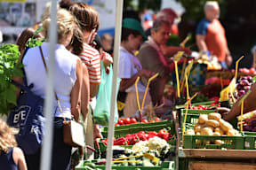 people buying fruits and vegetables at an outdoor market