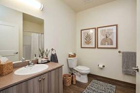 A bathroom with a toilet, sink, and mirror.