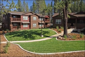 an image of an apartment complex with green grass and trees