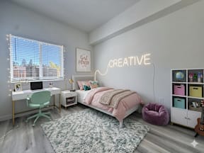 A bedroom with a bed, desk, chair, and a neon sign that says "Creative".
