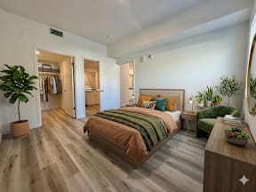 A bedroom with a bed, a plant, and a mirror.