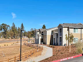 a row of houses with a sidewalk and a dirt field