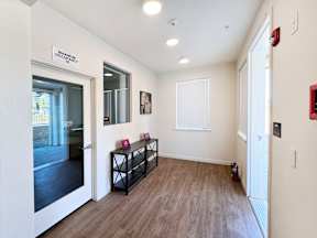 a hallway with a mirror and a door to a room with a wood flooring
