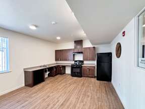 a kitchen and living room with wood flooring and a black refrigerator