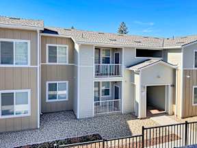 an exterior view of an apartment building with a driveway and balcony
