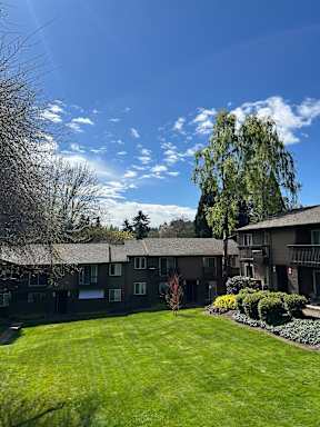 Apartment complex with a green lawn and trees.