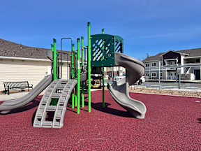 A playground with a green slide and a grey slide.