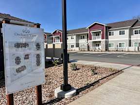 A sign for Orchard View Apartments stands in front of the building.