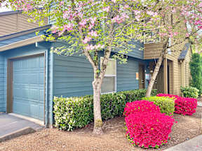 a blue house with a blue garage door and pink flowers