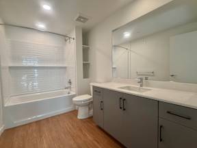 A white bathroom with a wooden floor and a white tub.