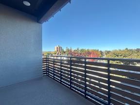 A balcony with a black railing overlooks a cityscape.