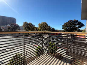 A parking lot with a metal fence in the foreground and a clear blue sky above.