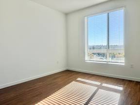 A room with a window and wooden flooring.