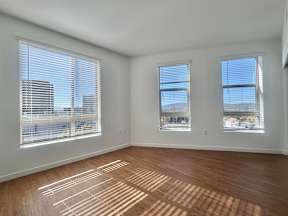 A room with wooden floors and three windows.