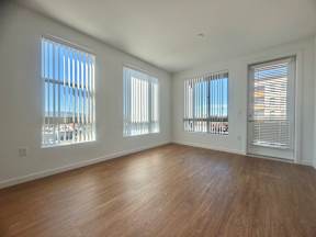 A room with wooden floors and three windows with blinds.