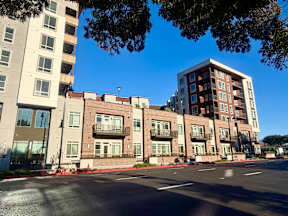 A street view of apartment buildings with a clear blue sky above.