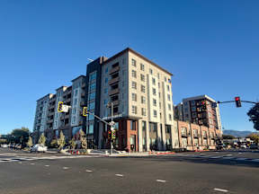 A street view of a multi-story building with a clear blue sky above.