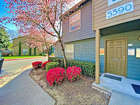 the front entrance of a home with a brown door and red flowers