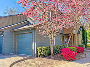 a house with a blue garage door and a tree with pink flowers