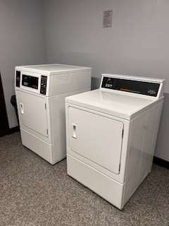 Two white air conditioners are stacked on top of each other.