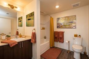 A bathroom with a toilet, sink, and a painting on the wall.