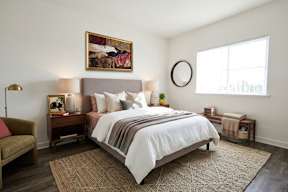 A bedroom with a large bed and a painting on the wall.