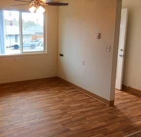 an empty living room with wooden floors and a window
