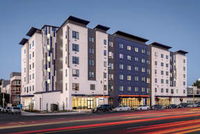 A large white and dark building with a parking lot in front.