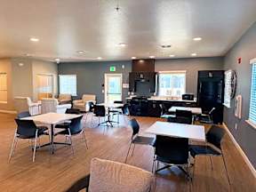 A room with a white table surrounded by black chairs.