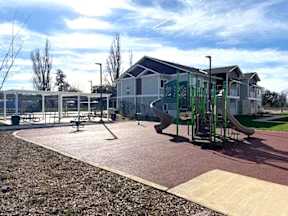 A playground with a slide, swings, and a seesaw.