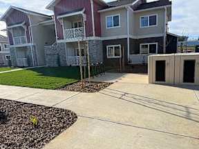 A row of houses with a concrete walkway in front.