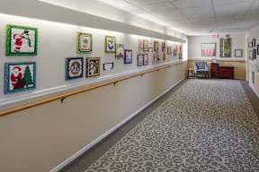 A hallway with framed pictures on the wall and a carpeted floor.