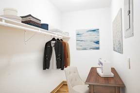 A room with a chair, a table, and a coat hanging on the wall.